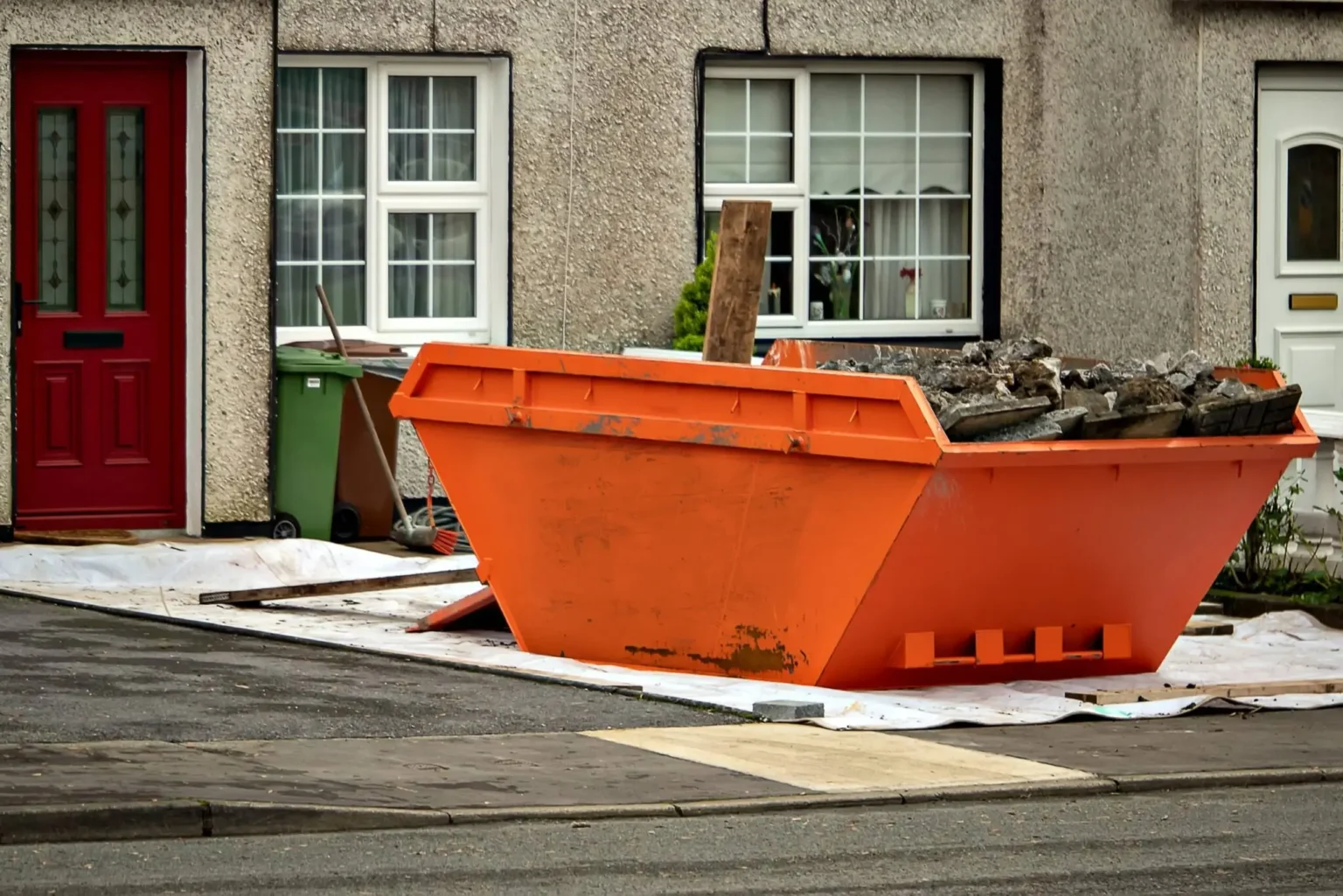 Residential property with an orange skip loaded with rubble and debris, from reliable skip hire Dorset solutions from Dorset Skips